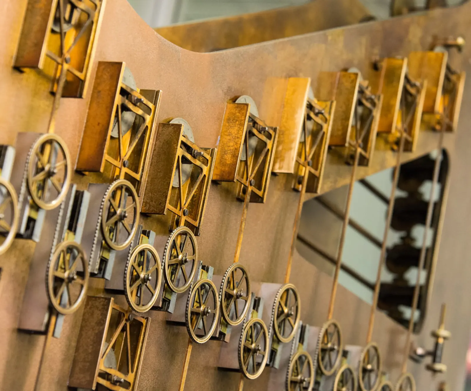 A close-up photograph shows brass gears and mechanical linkages mounted on a curved, copper-colored metal plate. The photographer titled it “Mechanically Adding Trigonometric Functions”.